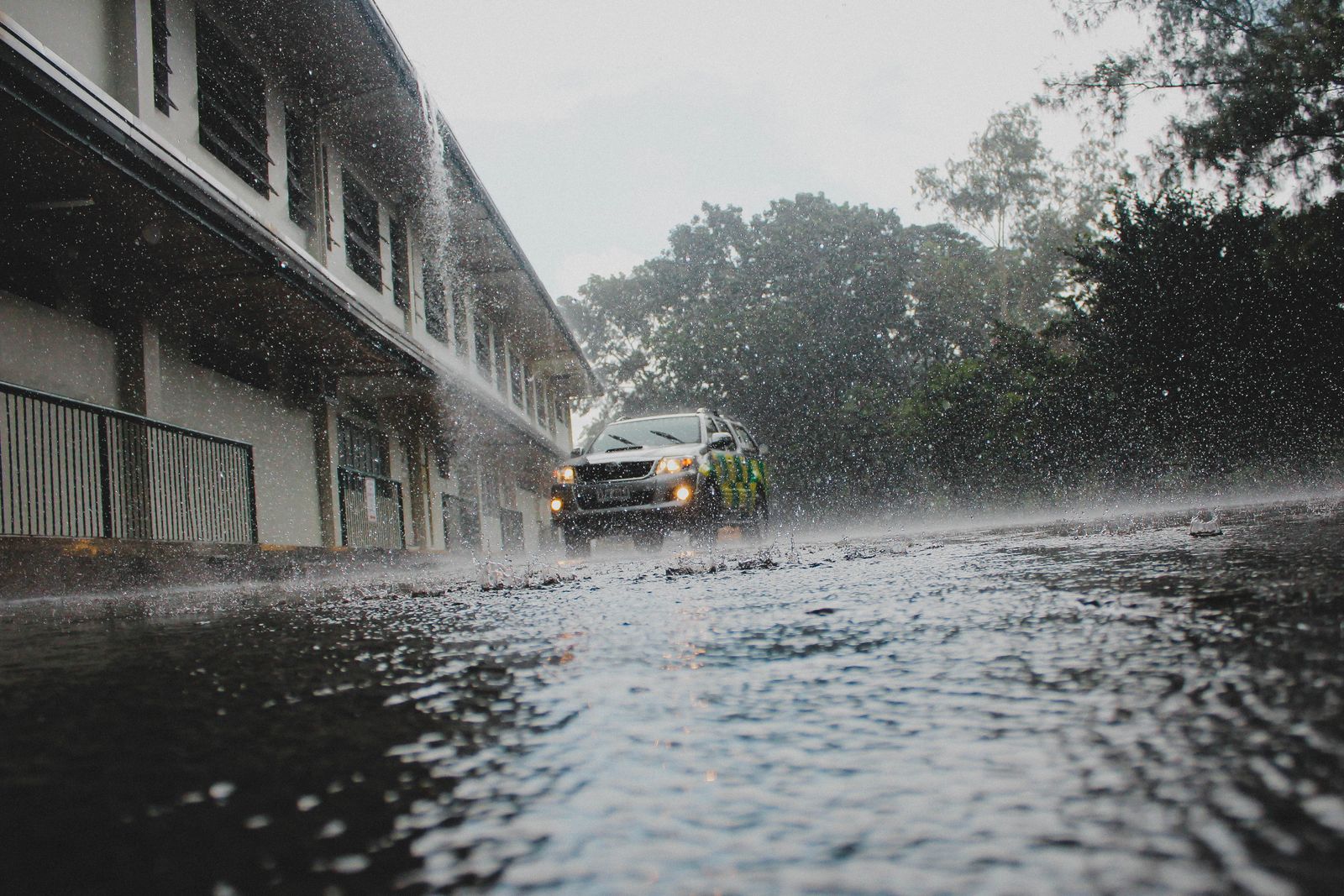 Coche circulando por una calle inundada bajo una lluvia intensa