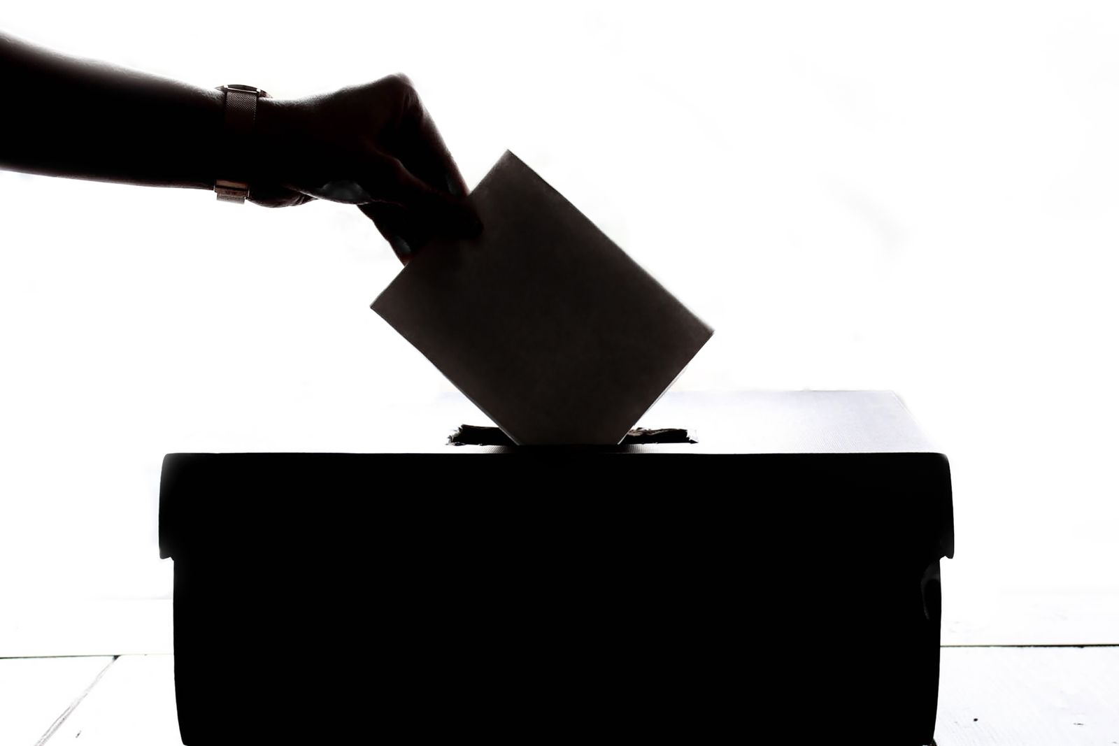 Mano depositando un voto en una urna