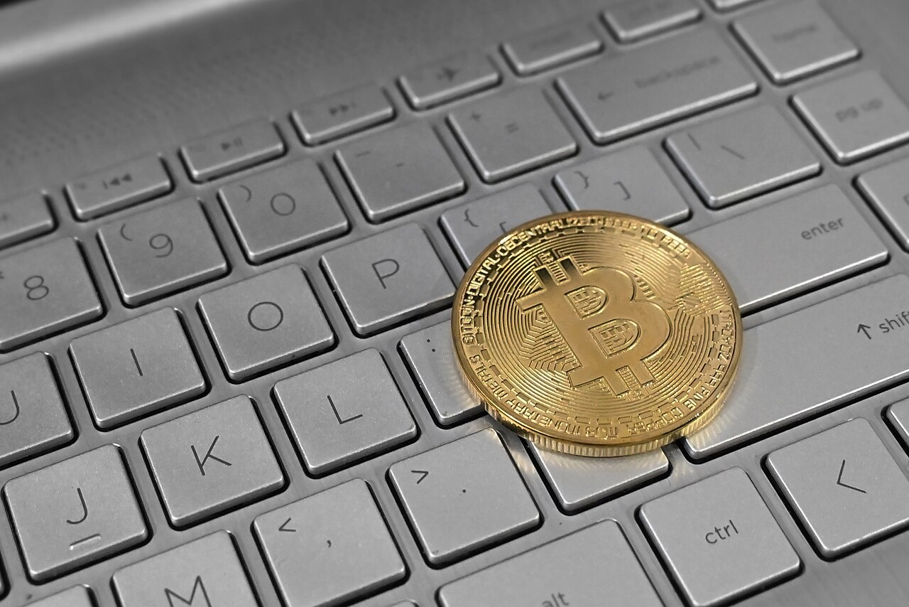 Moneda de bitcoin sobre el teclado de un ordenador portátil